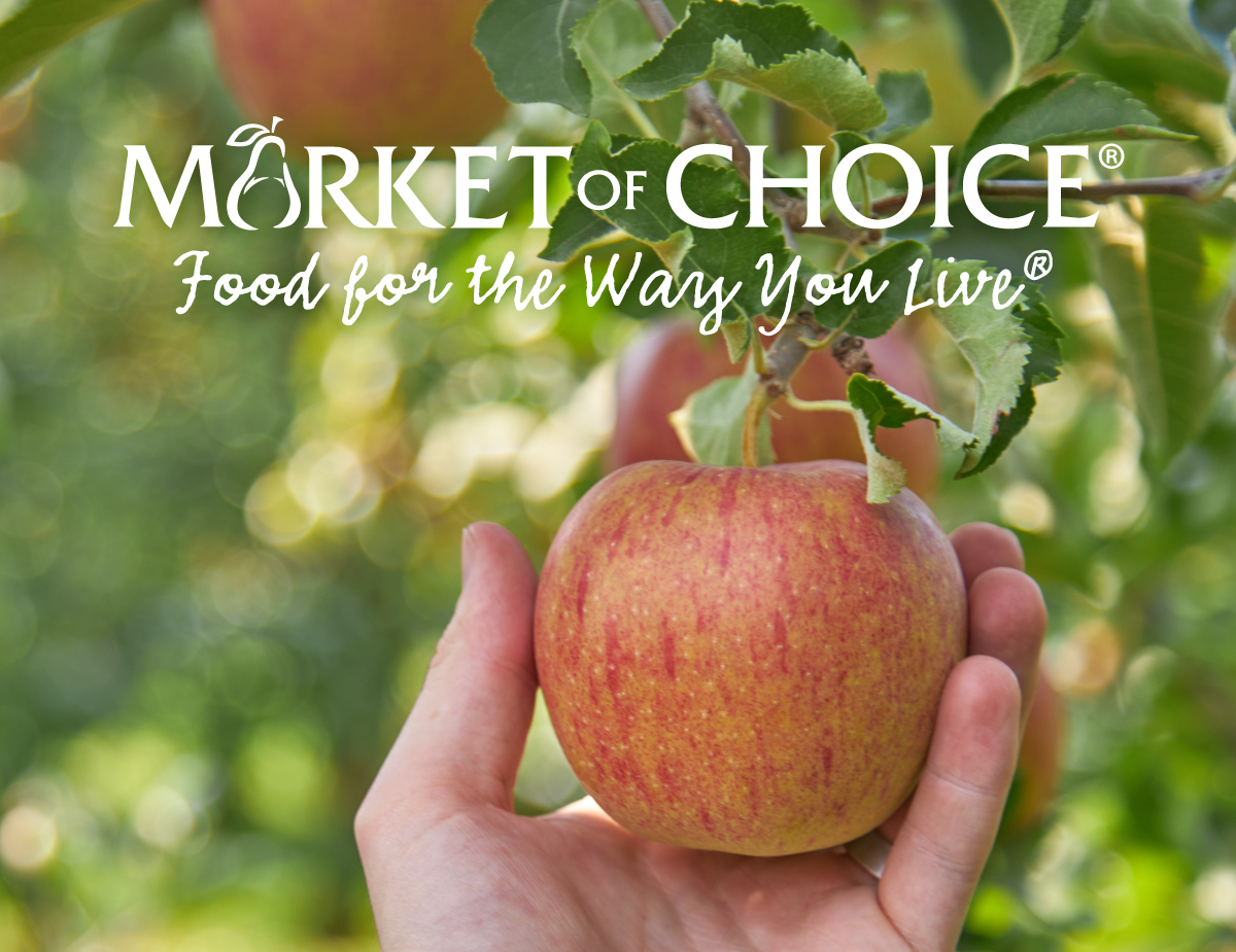 Text reads Market of Choice Food for the Way You Live, image is of a hand picking an apple